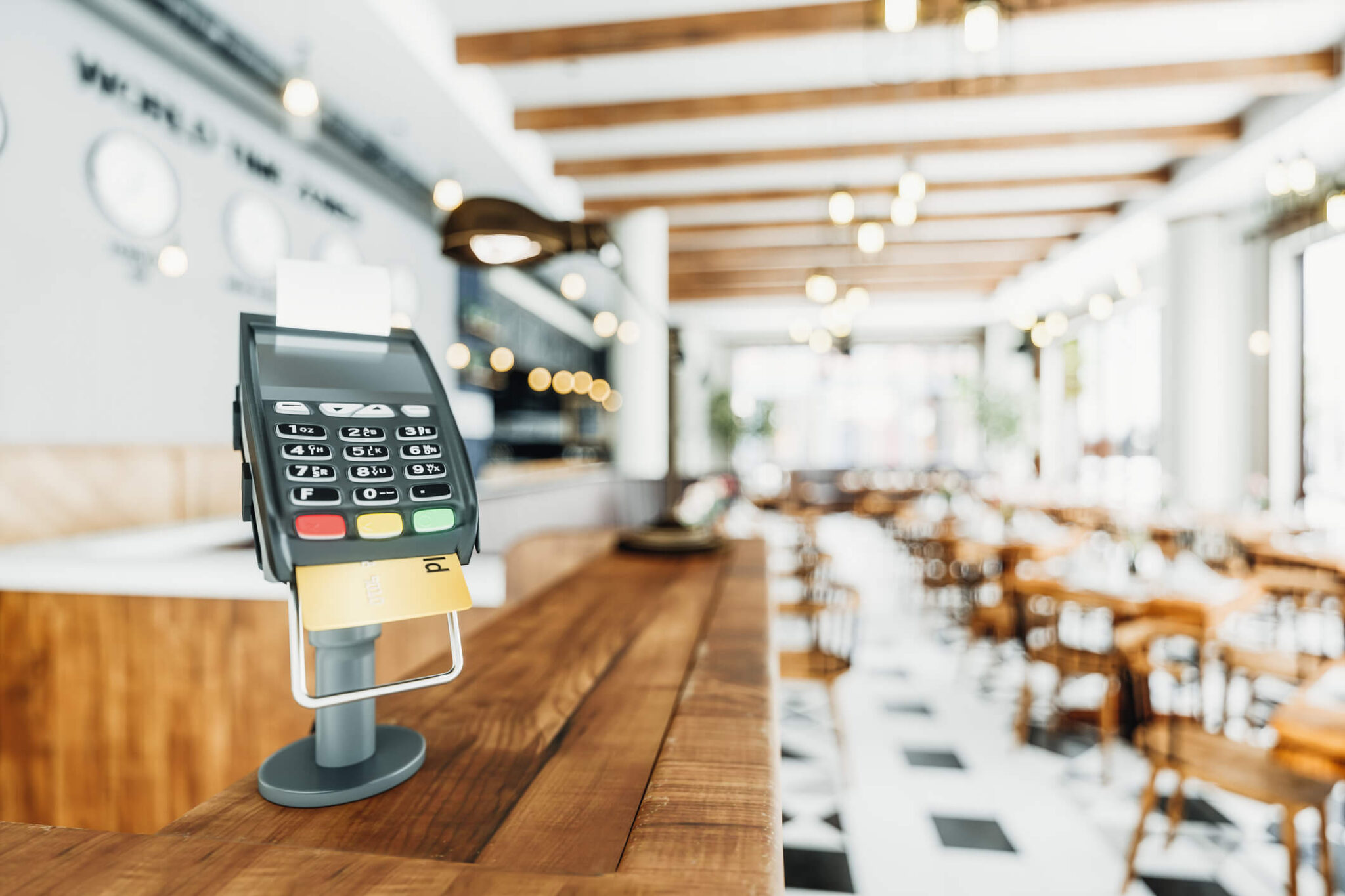 Pin pad sobre o balcão de um restaurante, com um cartão inserido para pagamento.